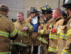 One fireman addressing group of firemen in uniform