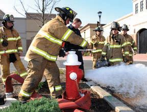 Firemen opening red fire hydrant with water gushing out