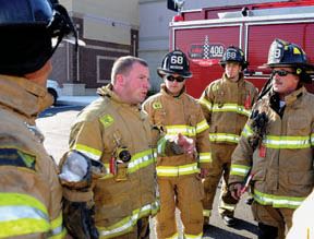 Fireman addressing group of firemen, all in uniform